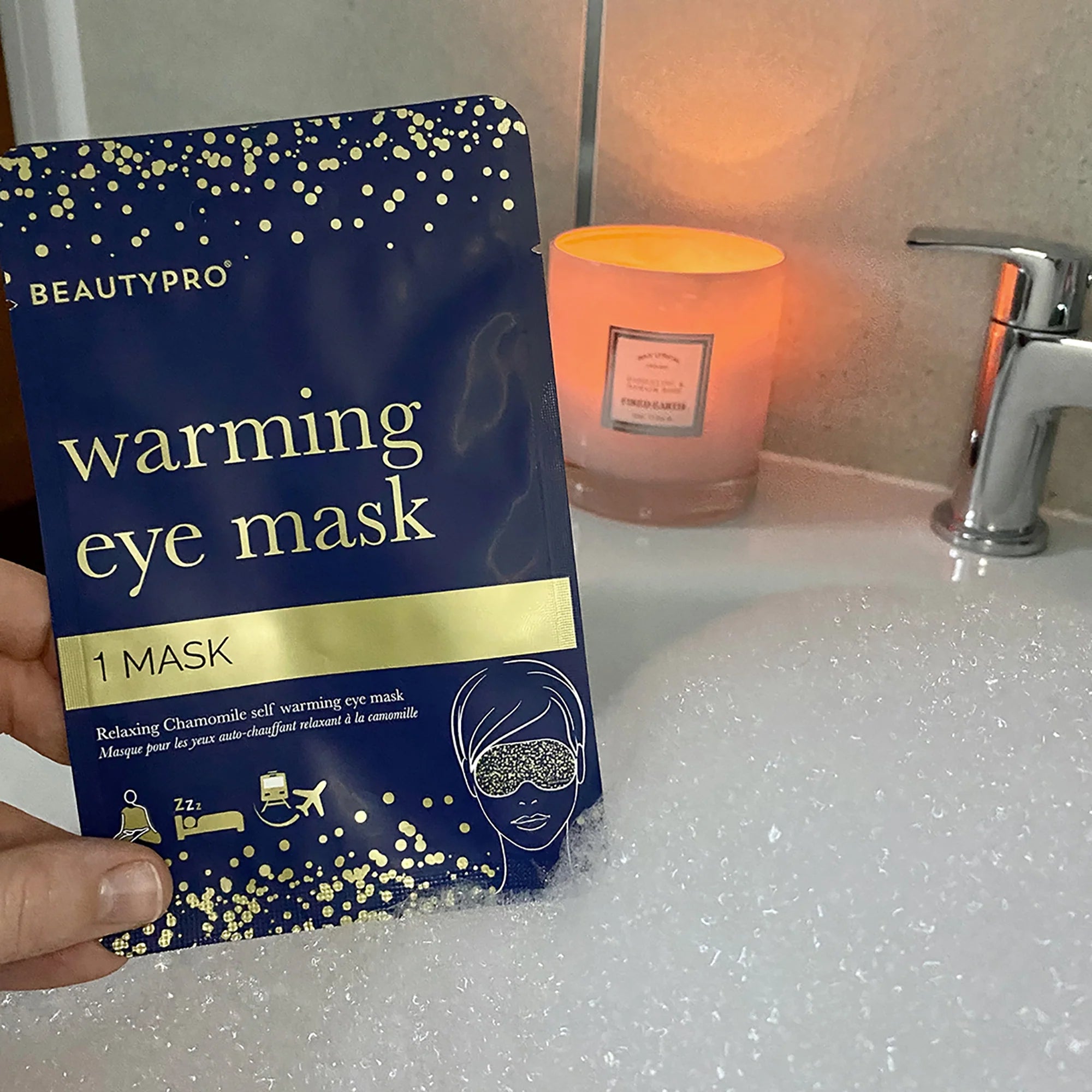 BeautyPro Warming Eye Mask sachet beside lit candle in a calm, relaxing setting