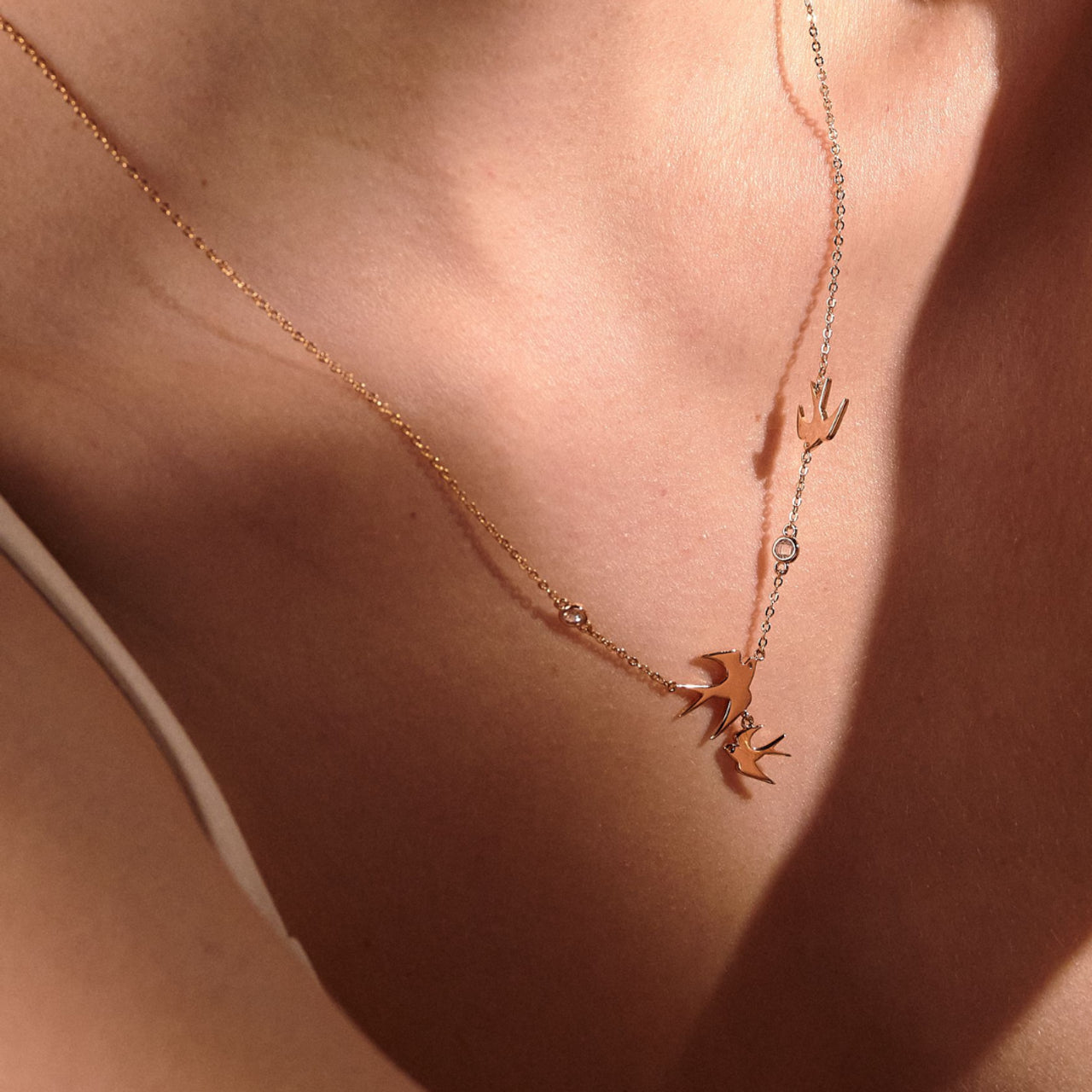 Close-up of Tipperary Crystal gold swallow pendant necklace worn on ladies neck