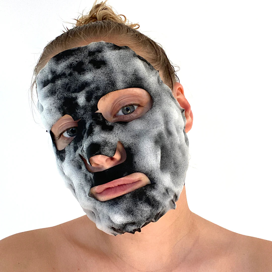 Woman using BeautyPro self-foaming detoxifyingcharcoal sheet mask on face