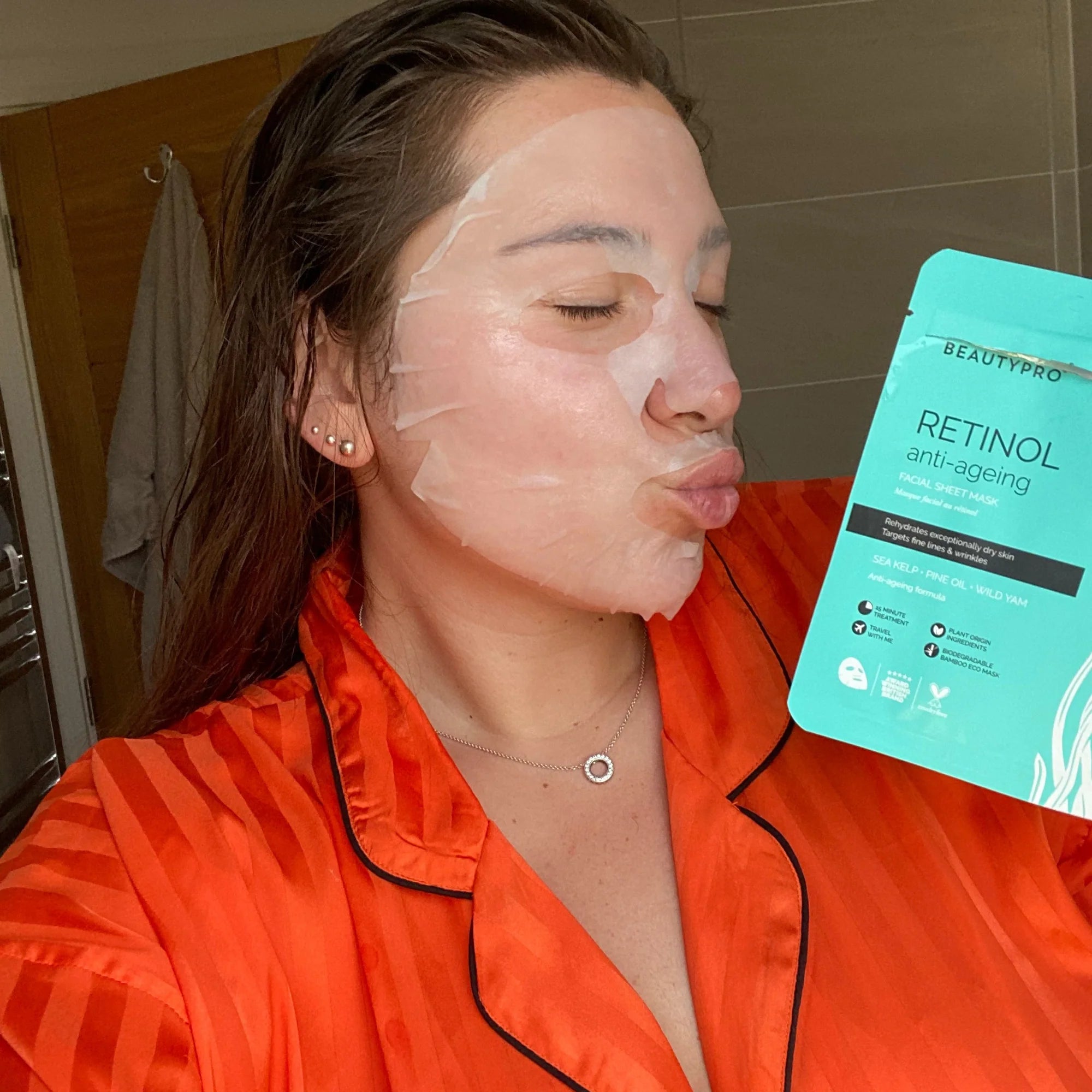 Woman using the sheet mask and holding packaging