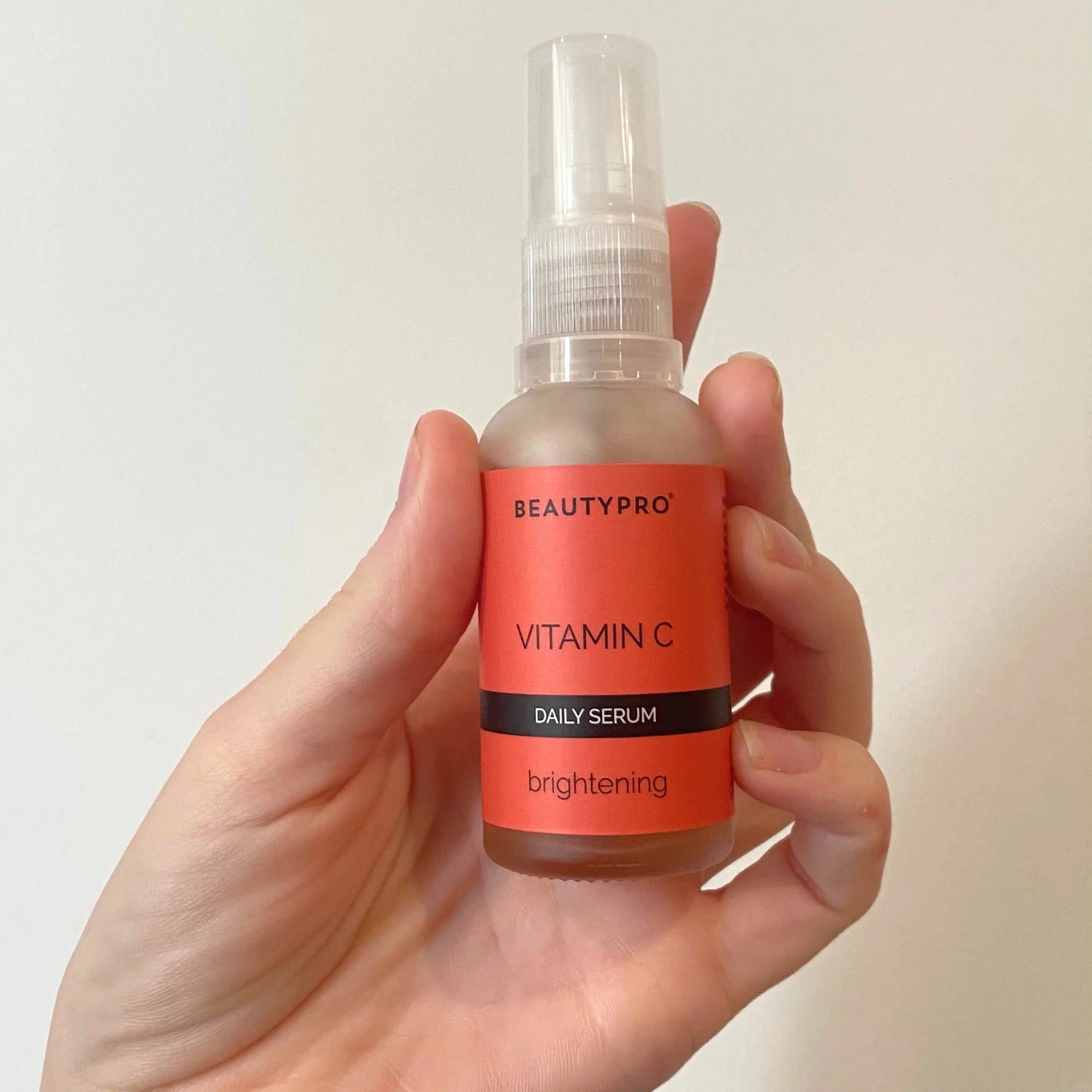 Holding BeautyPro Vitamin C serum bottle for daily skincare application