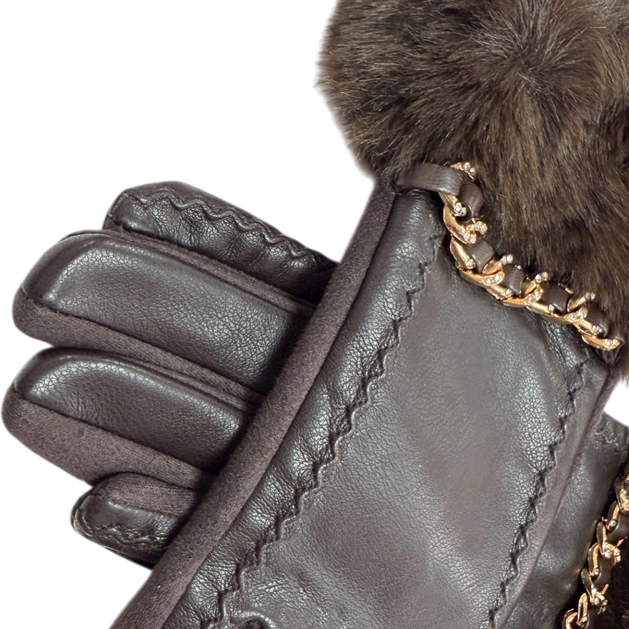 Close-up of brown winter gloves showing faux fur and gold chain