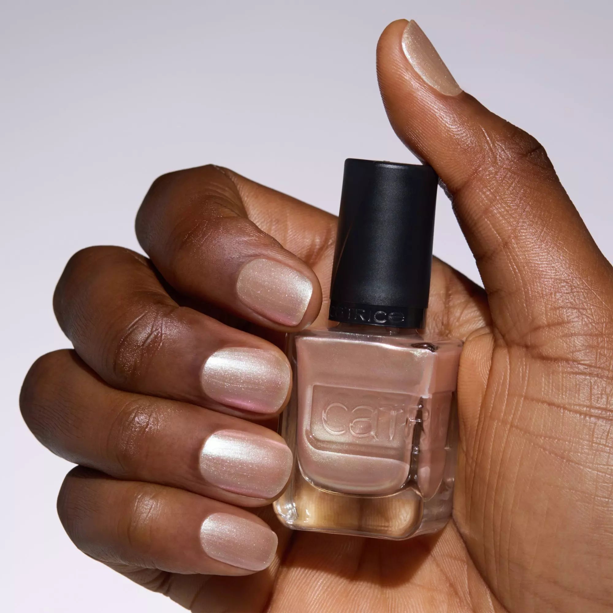 Hand holding Catrice Gel Affair The Pearl Next Door nude shimmer nail polish