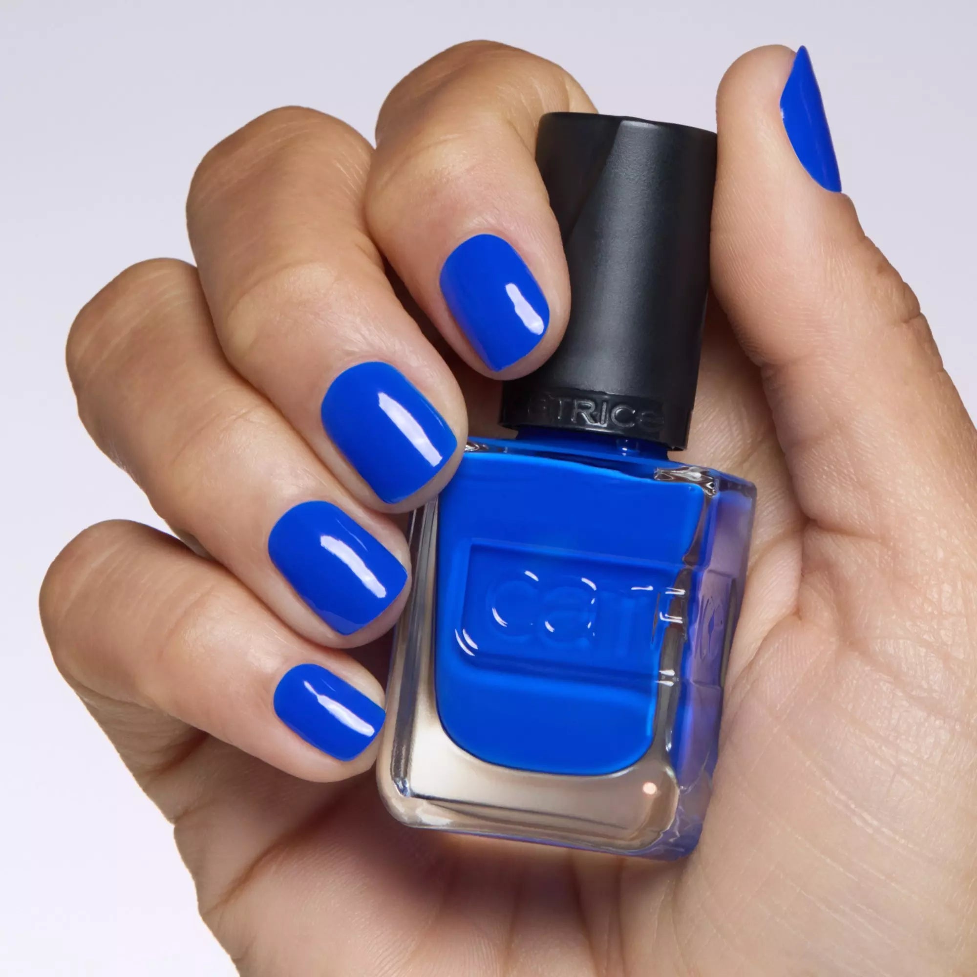 Model holding Catrice Gel Affair Your Royal Highness cobalt blue nail polish with manicured nails