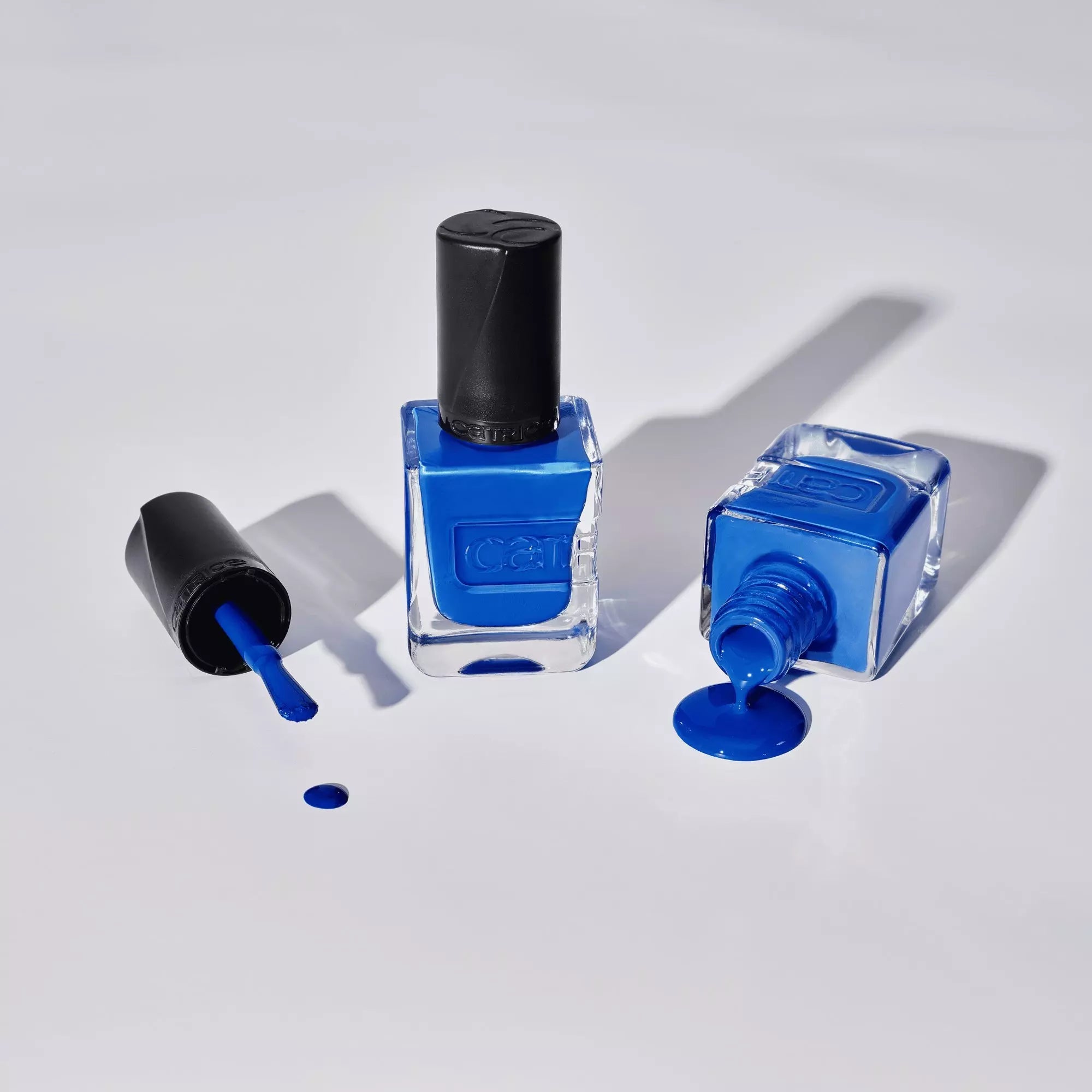 Flatlay of Catrice Gel Affair Your Royal Highness blue nail polish bottles and spills