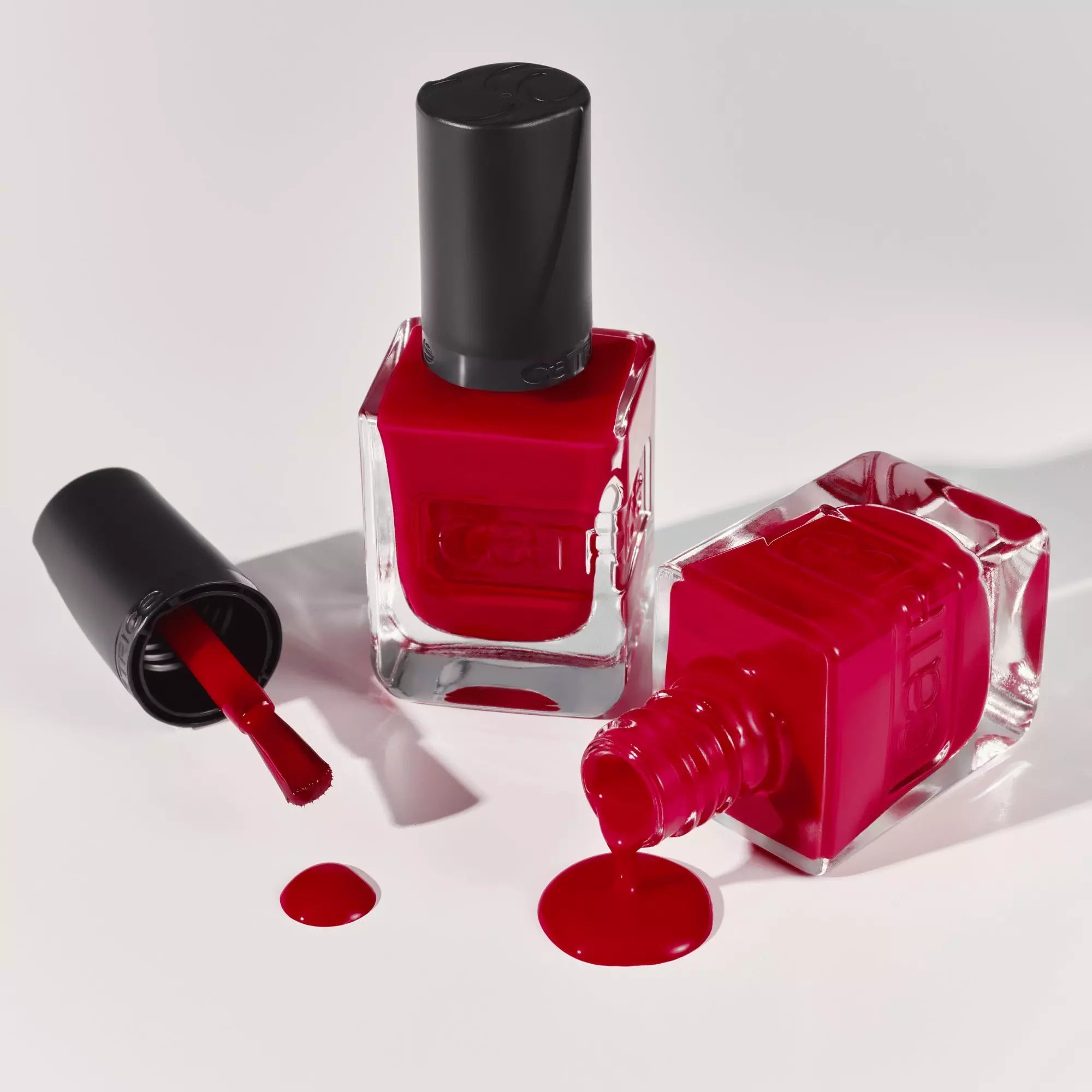 Red Catrice nail lacquer bottle with brush and gel polish spill
