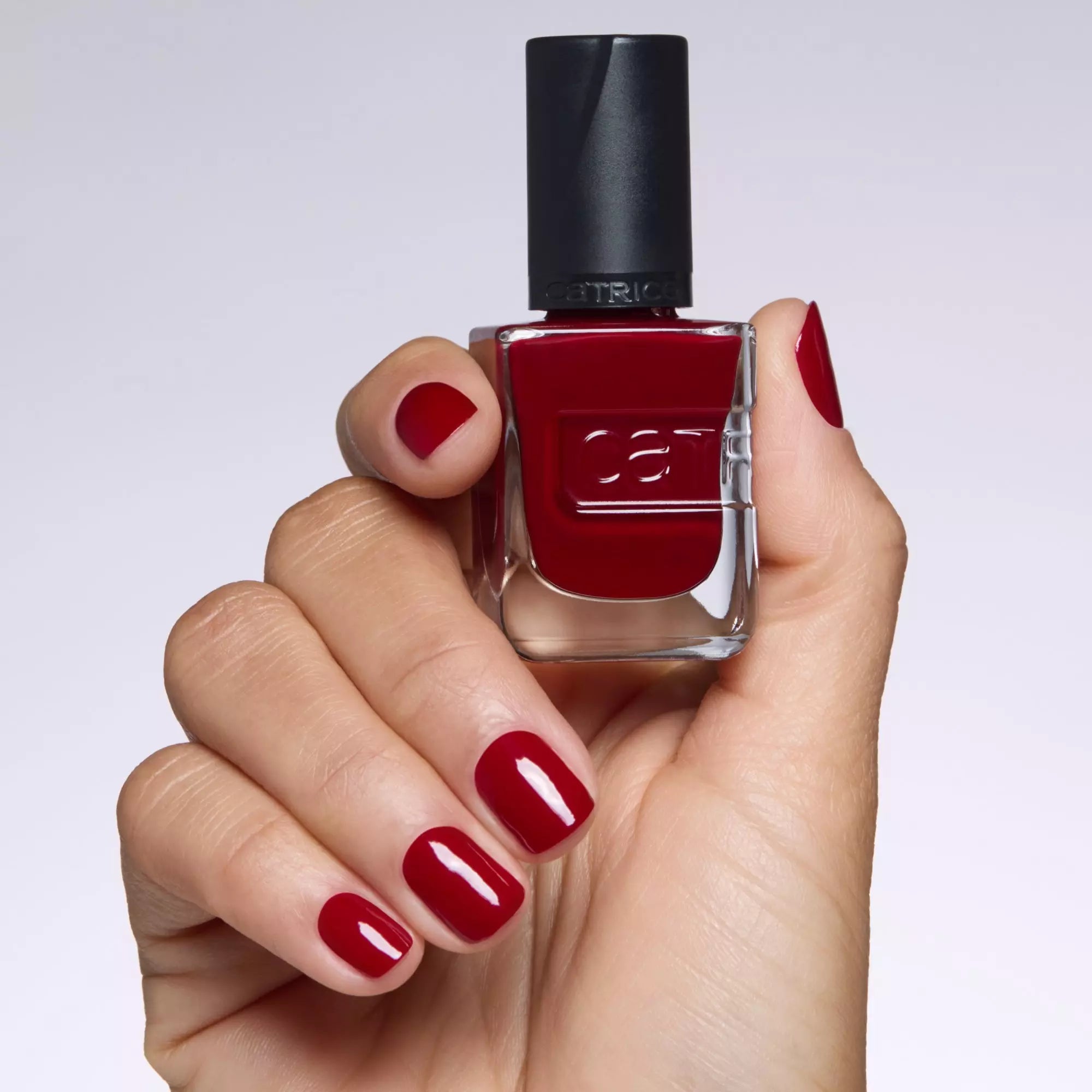 Hand holding Catrice Gel Affair Caught On The Red Carpet Nail Polish - Gel-Like Dark Red Finish