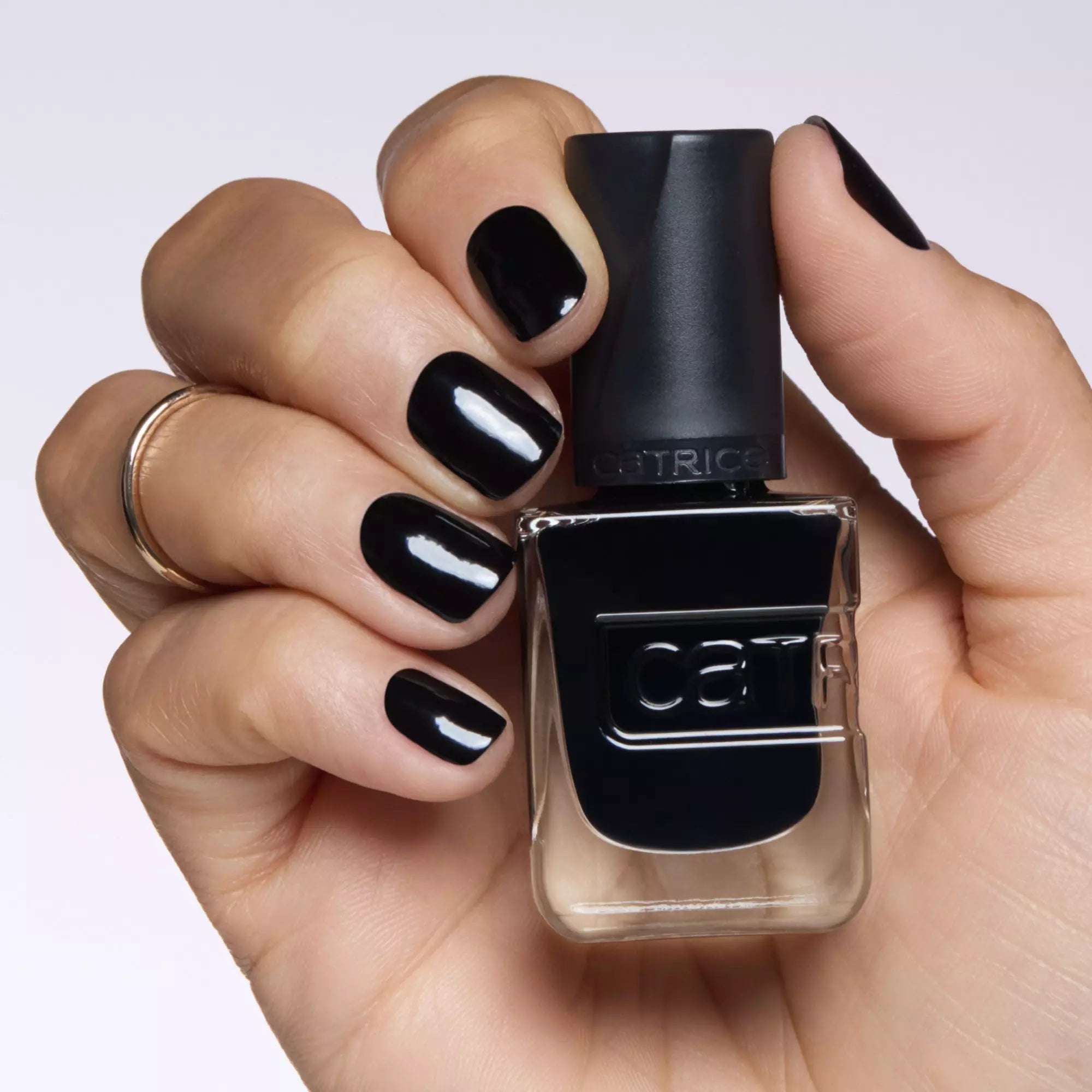 Model holding Catrice Gel Affair Black To The Roots nail polish bottle with glossy black nails