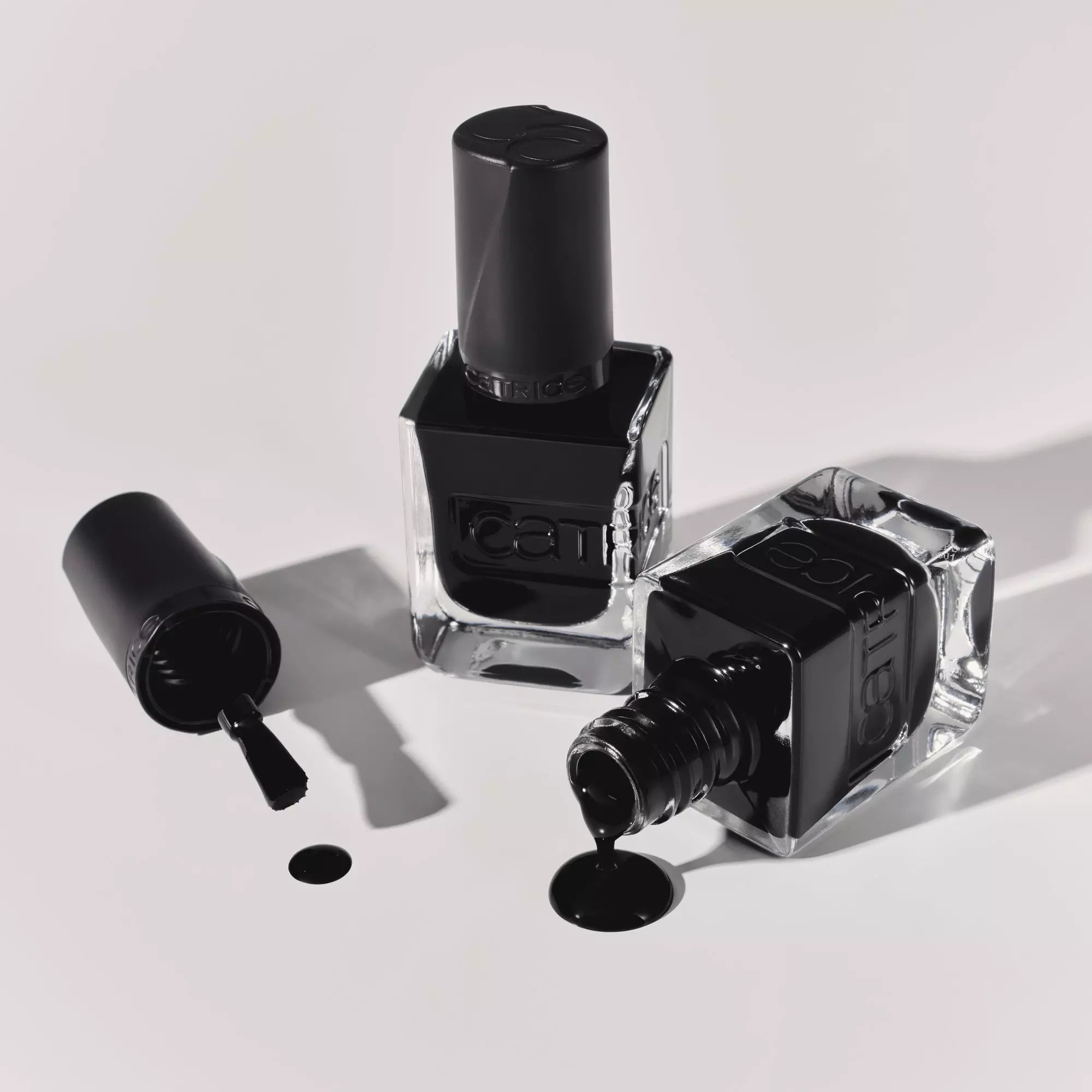 Flatlay of Catrice Gel Affair Black To The Roots nail polish bottles and spilled polish