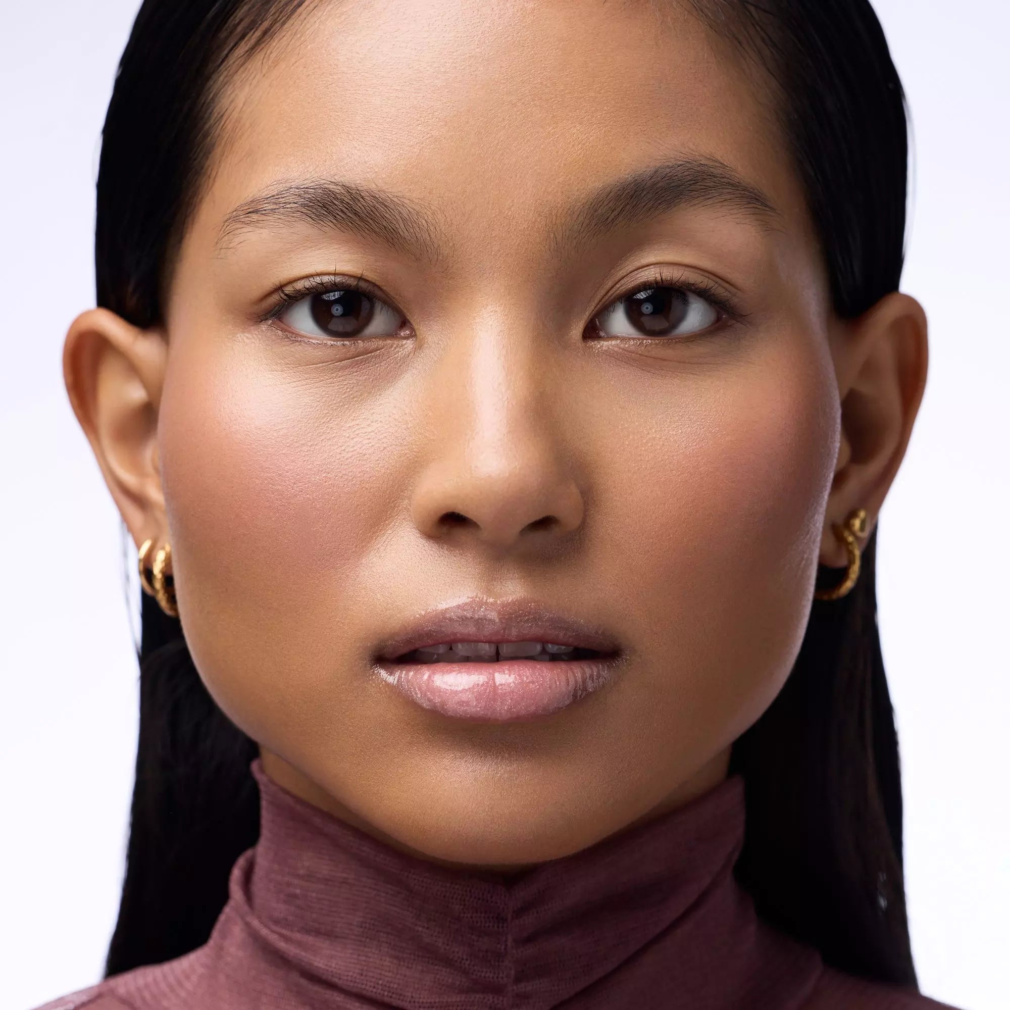 Model with medium skin tone wearing Catrice Max It Up Lip Booster 070 pink pearl plumping gloss