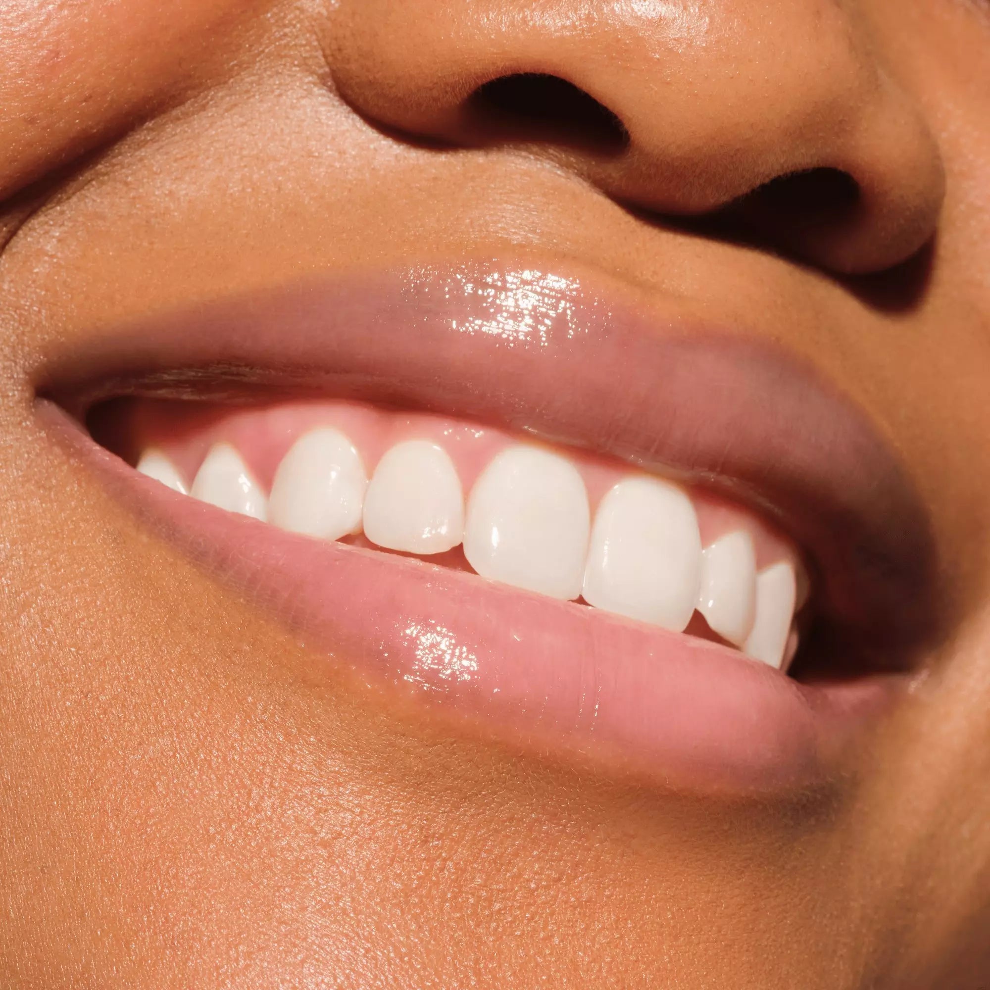Model wearing Catrice 010 More Amore lip gloss – soft pink shade on dark skin tone