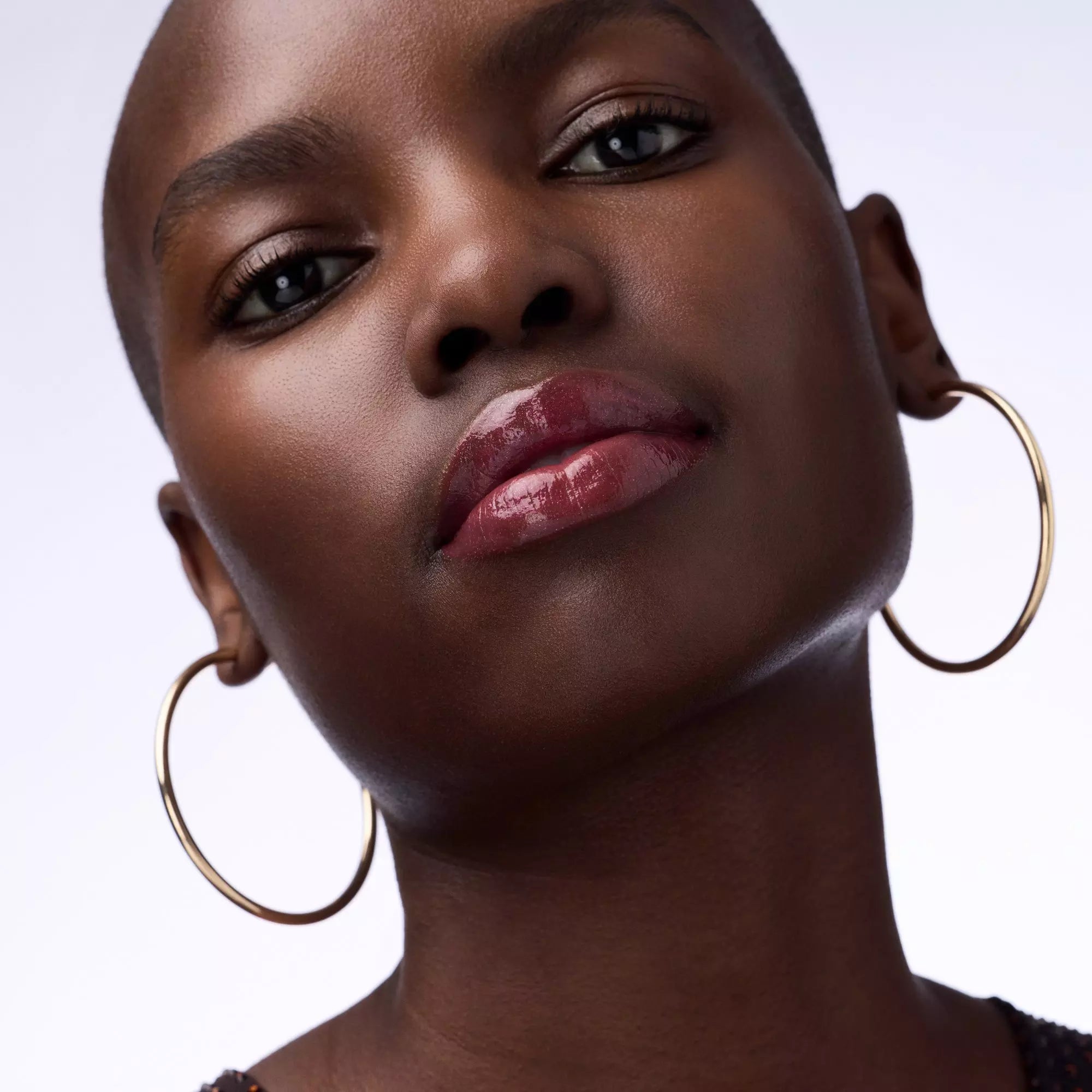 Deep skin tone model with high-shine red gloss from Catrice Lip Plumper 050