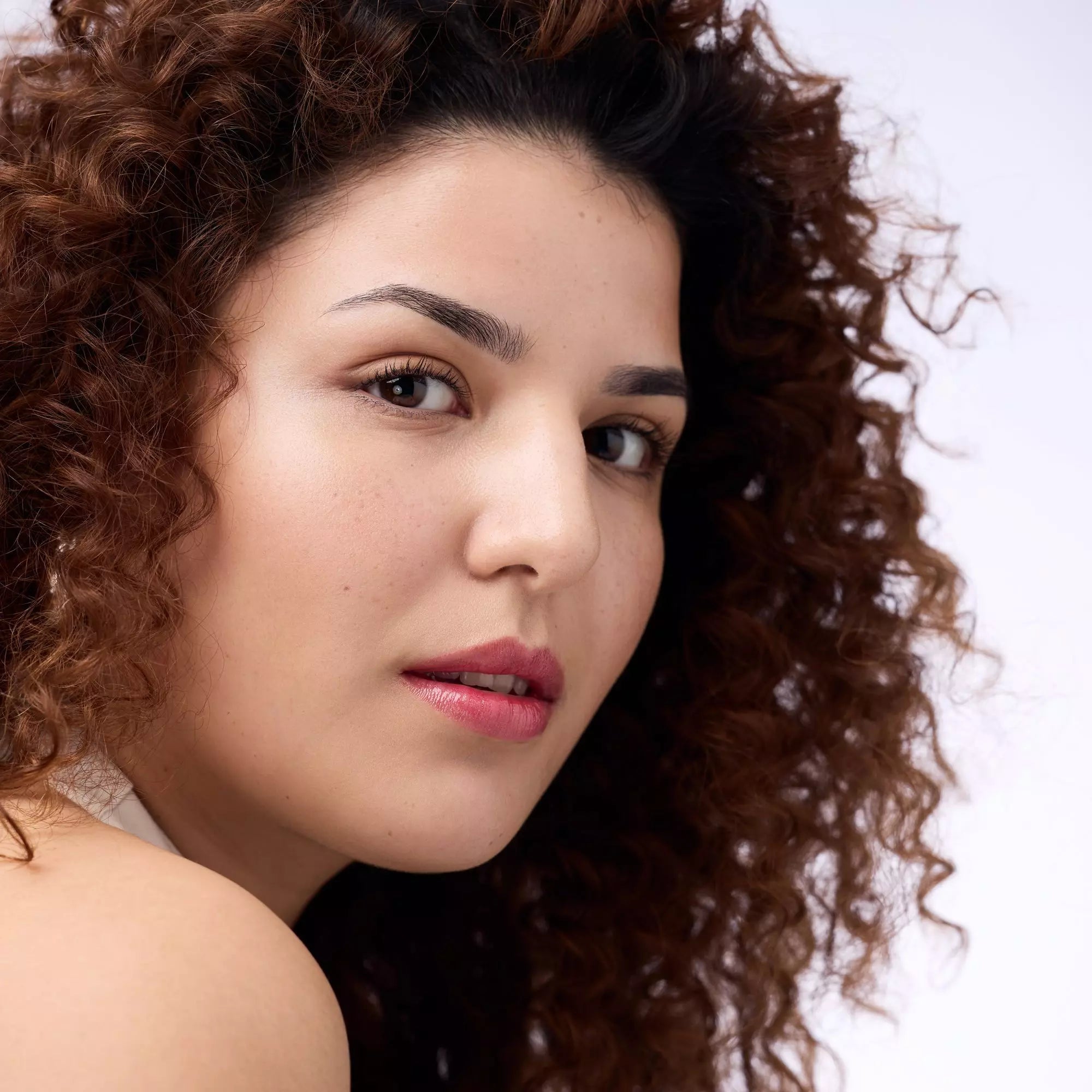 Model wearing Catrice Lip Plumper 050 with glossy red shimmer finish
