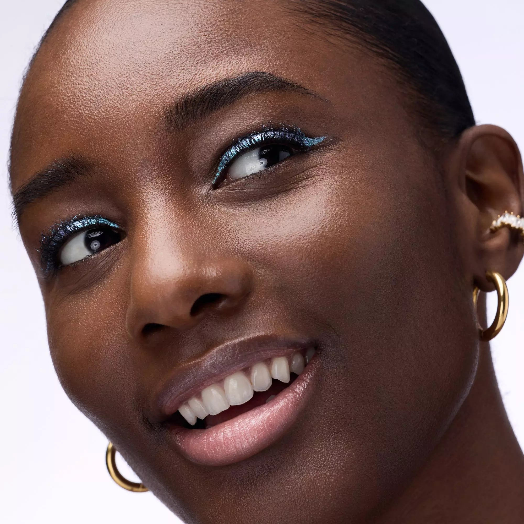 Model with dark skin wearing Catrice chrome blue liquid eyeliner on upper lash line