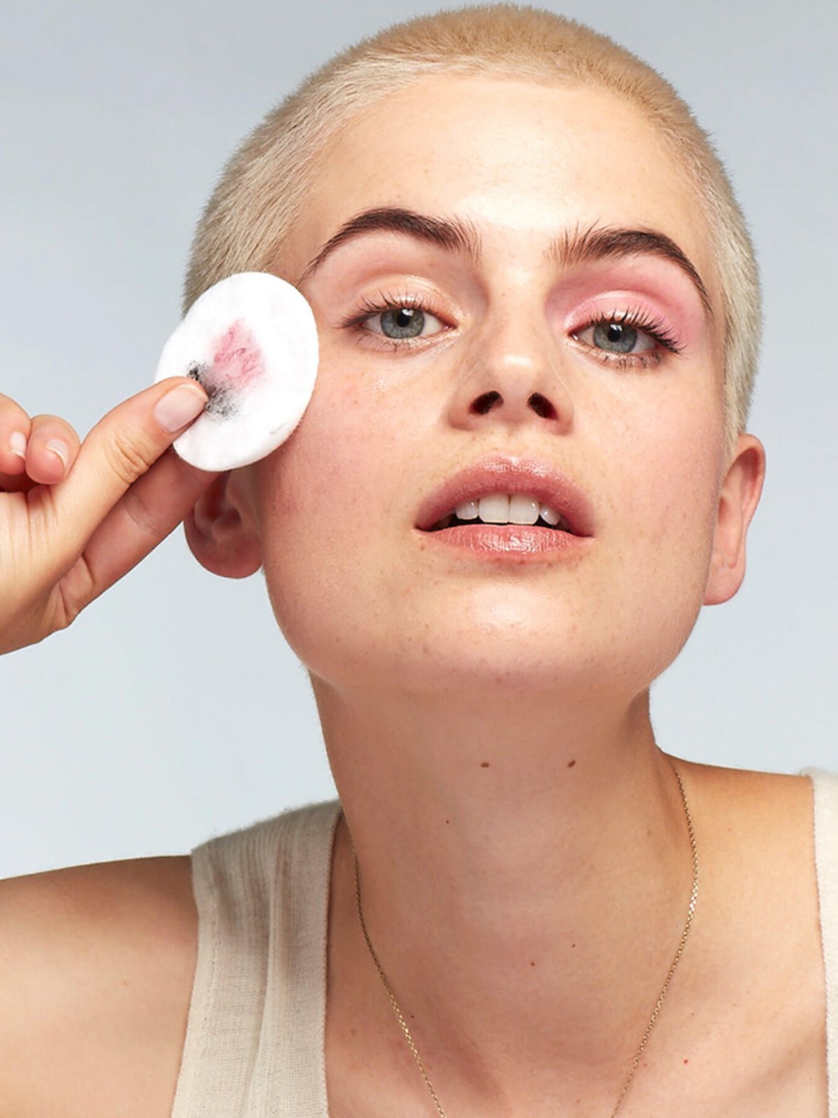 Woman cleansing her face with Garnier Hyalyronic Aloe Micellar Water on a cotton pad