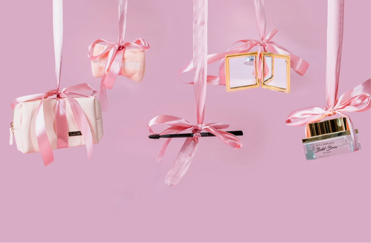 Illuminate by Shauna beauty gift accessories hanging from pink ribbons with mirror, makeup bag and brow tool
