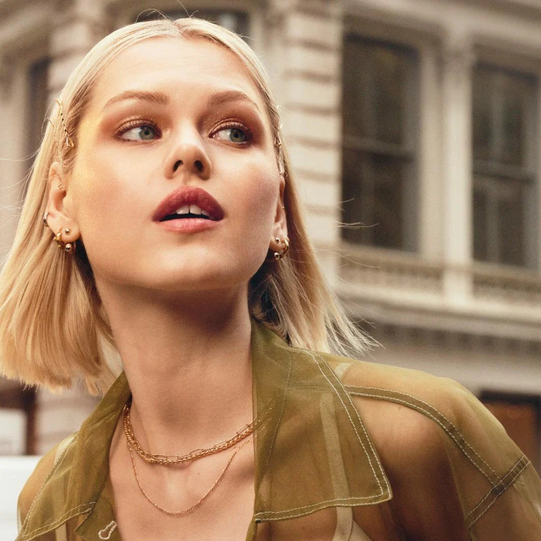 Model wearing Maybelline Sun Kisser All Star Highlighter outdoors with golden glow