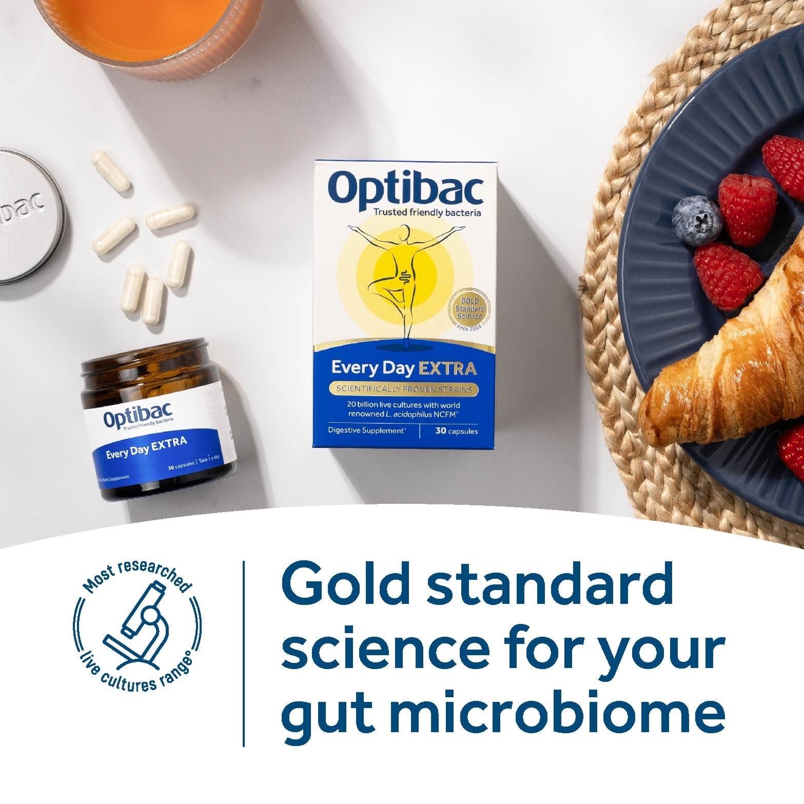 Optibac Every Day EXTRA probiotic jar beside healthy breakfast foods on kitchen counter.