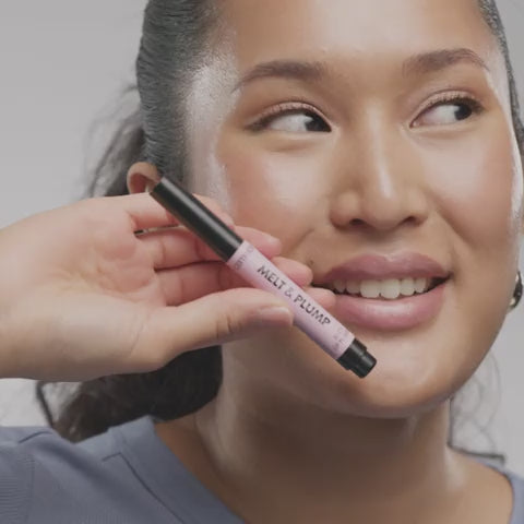Model holding Catrice Melt & Plump Lip Plumper 010 More Amore – smiling with glossed lips

