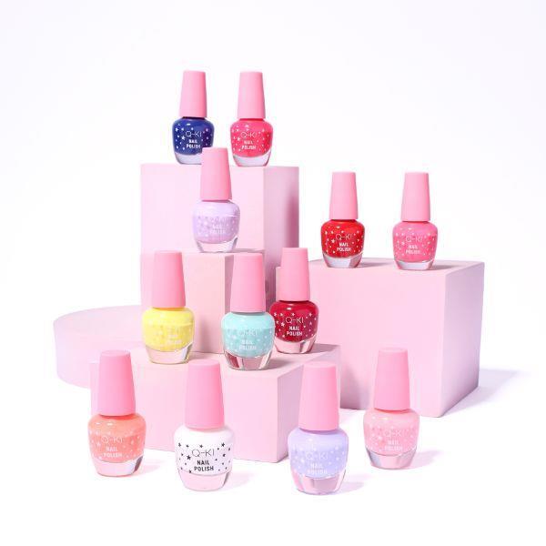 Q-KI Colour Care mini nail polishes in assorted colours with pink caps, displayed on pink blocks.