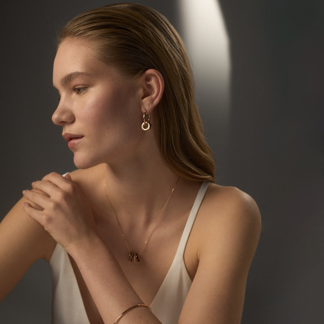 Gold and black enamel drop hoop earrings from the HALO Eclipse collection styled on model