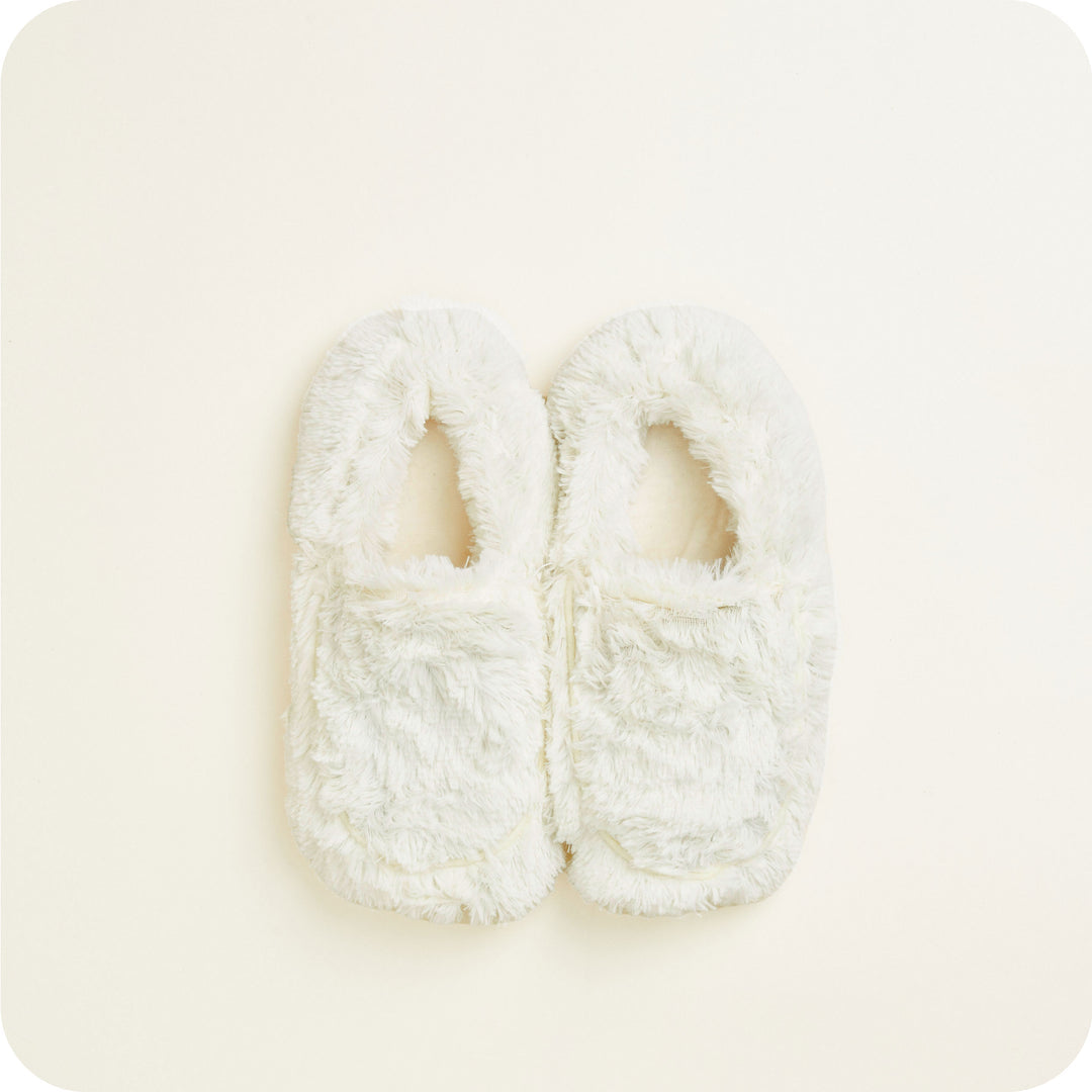Warmies slippers flat lay — ivory microwavable slippers pair, detailed warm fur texture.