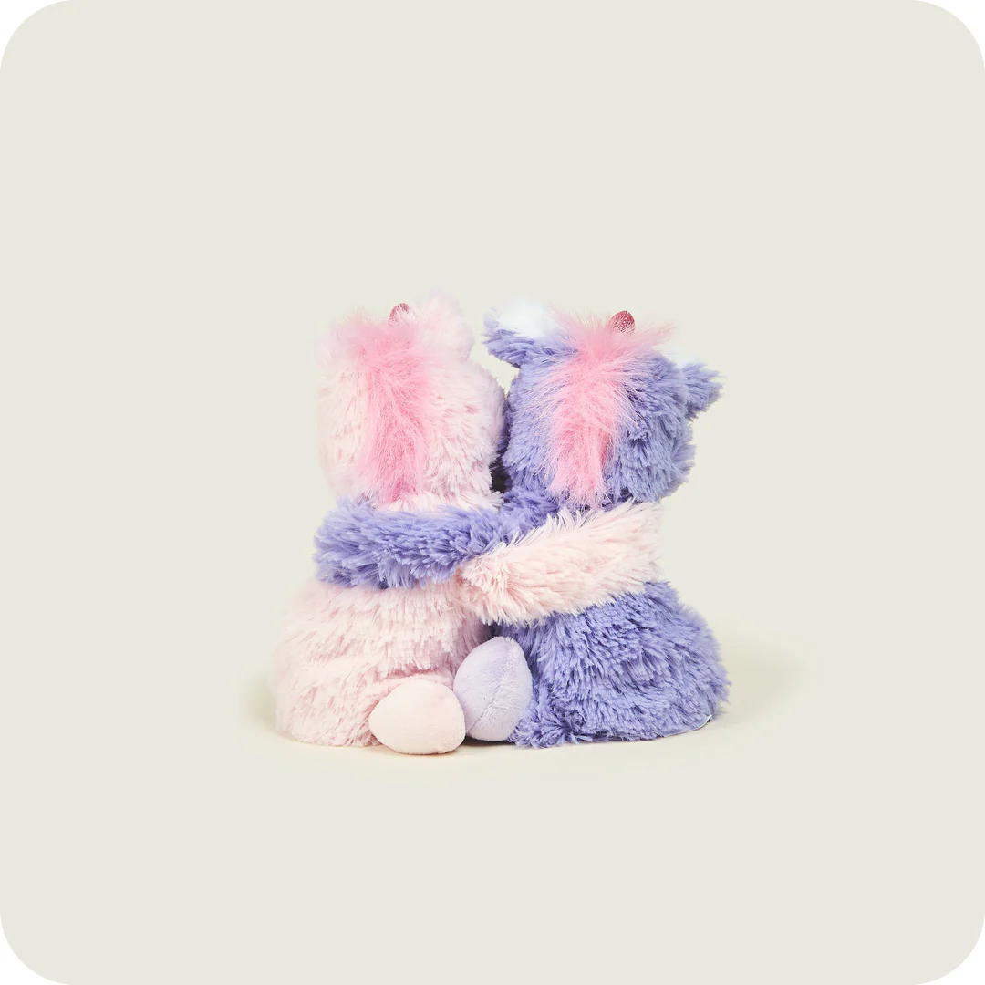 Warmies unicorns back view — seated pink and purple heatable soft toys for kids with weighted design and fur texture.