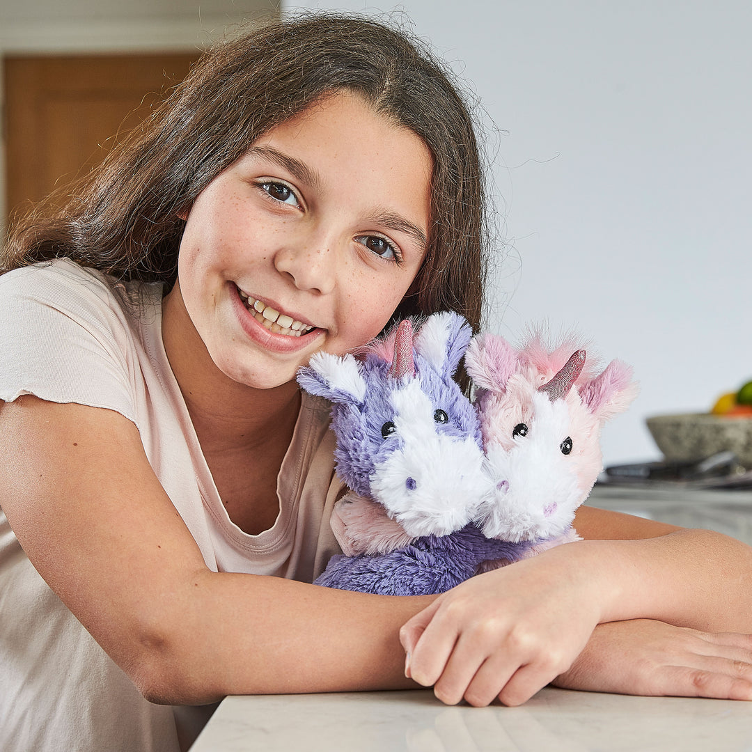 Older Child hugging Warmies unicorns — reheatable lavender-scented plush used for calming, sensory support and bedtime.